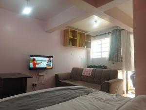 a living room with a couch and a tv at Masqani studios muthiga in Rungiri