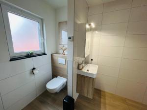 a bathroom with a toilet and a sink and a window at Ons huisje in Schoot in Budel-Schoot