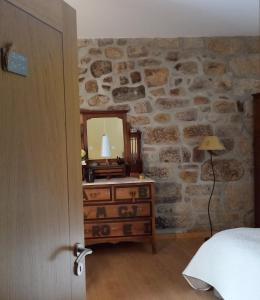 a bedroom with a stone wall with a dresser and a mirror at Cantinho do Ribeiro in Lourosa da Trapa