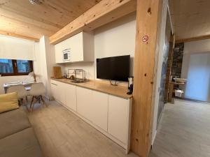 a kitchen with white cabinets and a flat screen tv at Pensión ARISTONDO Boutique Pentsioa in Getaria