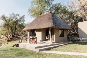 a small hut with a thatched roof and a table at Timbila Game Lodge - Welcome to Land of Leopards and Buffalo in Phalaborwa