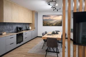 eine Küche mit Tisch, Stühlen und Fernseher in der Unterkunft FalHouse- luksusowe apartamenty z jacuzzi & sauna in Lesko