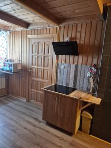 a kitchen with a island in a room with wooden walls at Miodowa Chatka in Brzegi