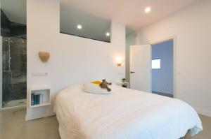 a white bedroom with a cat sitting on a pillow on a bed at Casa Langlois in Telde