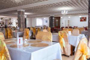 a banquet hall with white tables and yellow chairs at Samal Resort and SPA in Taraz
