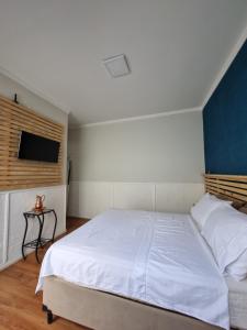a bedroom with a white bed and a flat screen tv at Loft em Butantã, próximo a USP in São Paulo