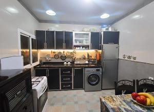 a large kitchen with black cabinets and a dishwasher at Martil Beach Apartment in Martil +9 photos
