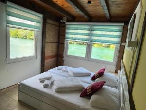 a bedroom with two beds with pillows and two windows at Hotel River View bihac in Lohovo