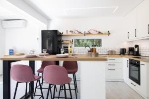 a kitchen with a counter with pink stools at The Olive Grove Cottage by Konnect - 2,5km from Ipsos in Ipsos +14 photos