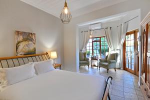 a bedroom with a large white bed and two chairs at Mimosa Lodge in Montagu +65 photos