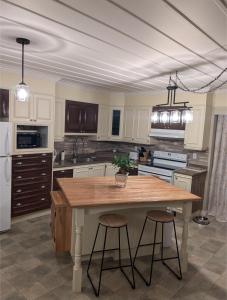 a kitchen with a wooden table and two bar stools at La belle ancestrale in Sainte-Anne-des-Monts