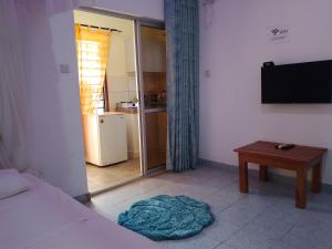 a room with a bed and a table and a television at Kamsons in Mombasa