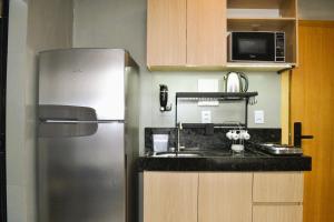 a kitchen with a stainless steel refrigerator and a microwave at Real Grandeza - Studios modernos in Aparecida de Goiânia