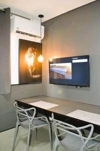 a table with two chairs and a tv on a wall at Real Grandeza - Studios modernos in Aparecida de Goiânia