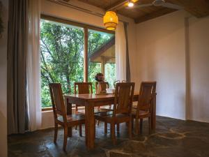 a dining room with a table and chairs and a window at Kuhama Private Mountain Chalet Naggar in Nagar