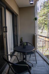 a table and chairs on a balcony with a window at Dawn's Place in Harare
