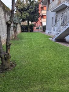 a green yard with a tree next to a building at Casafiorella in Monza