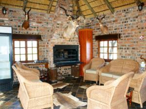 a living room with wicker chairs and a brick wall at Witgatboom Boskamp in Naboomspruit