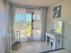 a bedroom with a bed and a window with a desk at VitaminSea in Mossel Bay