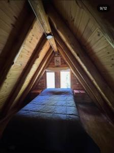a bed in a attic with a window in it at Cabañas de montaña Triskel in Aluminé