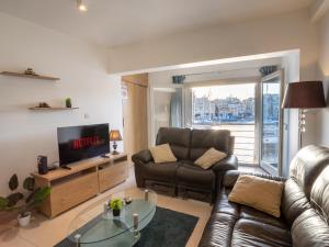 a living room with a leather couch and a television at Birgu Seafront 3 Bedroom Apartment in Vittoriosa