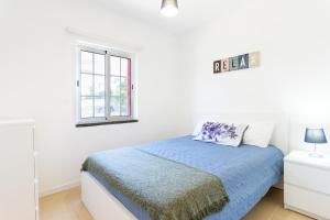 a white bedroom with a bed and a window at Picos House in Lajes do Pico