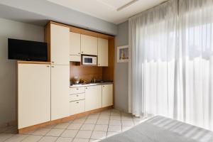 a kitchen with white cabinets and a tv and a window at Hotel Sport & Residenza in Cesenatico