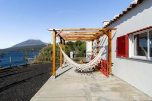 a hammock attached to a house with a view of the water at Picos House in Lajes do Pico