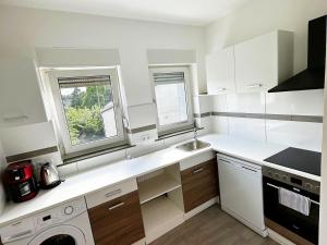 a white kitchen with a sink and two windows at Gemütliche Apartments in Herten in Herten