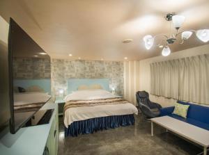 a bedroom with a bed and a tv and a couch at Hotel Flower Style koriyama tenri in Tenri