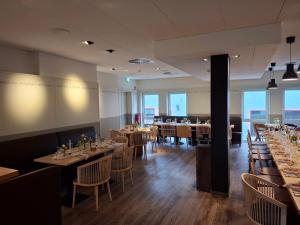 a dining room with tables and chairs and windows at EIFELkrimihotel in Hillesheim