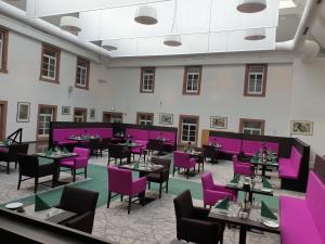 a dining room with purple chairs and tables at EIFELkrimihotel in Hillesheim +22 photos