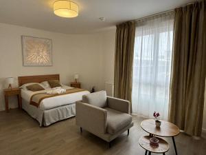 a bedroom with a bed and a chair and a window at DOMITYS - Le Solstice in Versailles +10 photos
