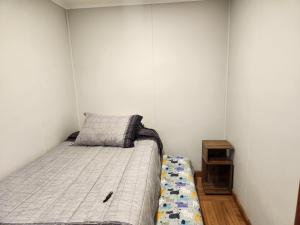 a small bedroom with a bed and a night stand at Cabaña Valle las Lengas in Punta Arenas