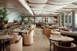 a restaurant with tables and chairs and a painting on the wall at Morea House, Autograph Collection in Cape Town