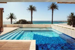 a swimming pool with palm trees and the ocean at Morea House, Autograph Collection in Cape Town