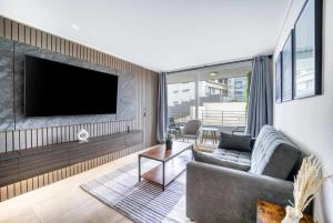 a living room with a couch and a tv on a wall at Eluchans One with Pool & parking near Reñaca Beach in Viña del Mar