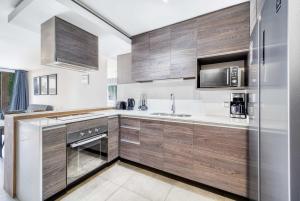 a kitchen with wooden cabinets and a stainless steel refrigerator at Eluchans One with Pool & parking near Reñaca Beach in Viña del Mar
