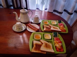 a wooden table with two green plates of breakfast foods at My Transit Stay Hotel - Near Airport in Negombo