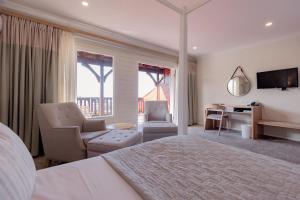 a bedroom with a bed and a desk and chairs at The Kelway Hotel in Port Elizabeth