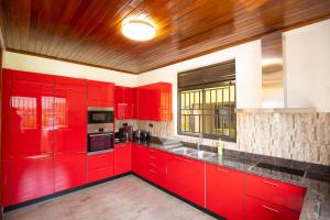a red kitchen with red cabinets and a wooden ceiling at Villa d'exception Rebero in Kigali