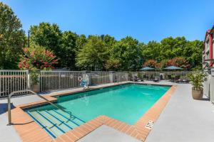 a swimming pool with a fence and trees at City Express by Marriott Duluth in Duluth