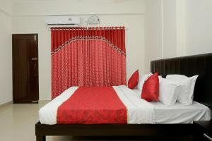 a bedroom with a bed with a red curtain at Hotel O Technopark Formerly Le Frank in Trivandrum +17 photos