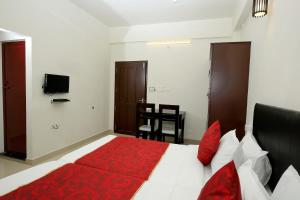 a bedroom with a large bed with a red blanket at Hotel O Technopark Formerly Le Frank in Trivandrum