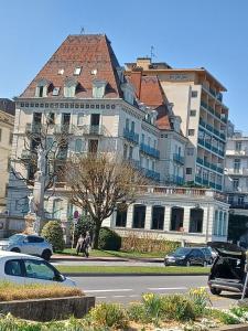a large building with cars parked in front of it at Le Beaupré face au lac Leman in Évian-les-Bains