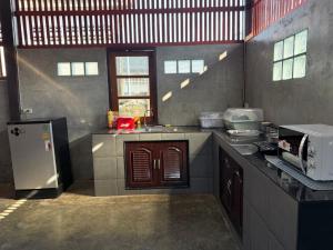 a kitchen with a stove and a refrigerator at TEAK HOUSE In TOWN in Mae Hong Son