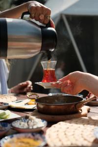a person pouring food into a pot on a table at Rida Sultan Konağı Kozbeyli in Eskiömerler