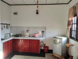 a kitchen with wooden cabinets and a refrigerator at Moon Light Rest in Galle
