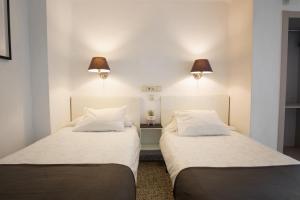 two beds in a room with two lamps on the wall at Hostal On Dormire Valencia in Valencia