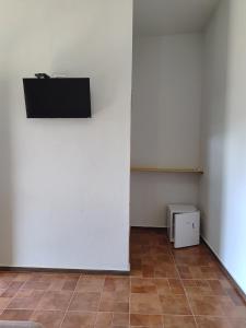 a room with a white wall and a television at Chalésforquilha in Delfinópolis